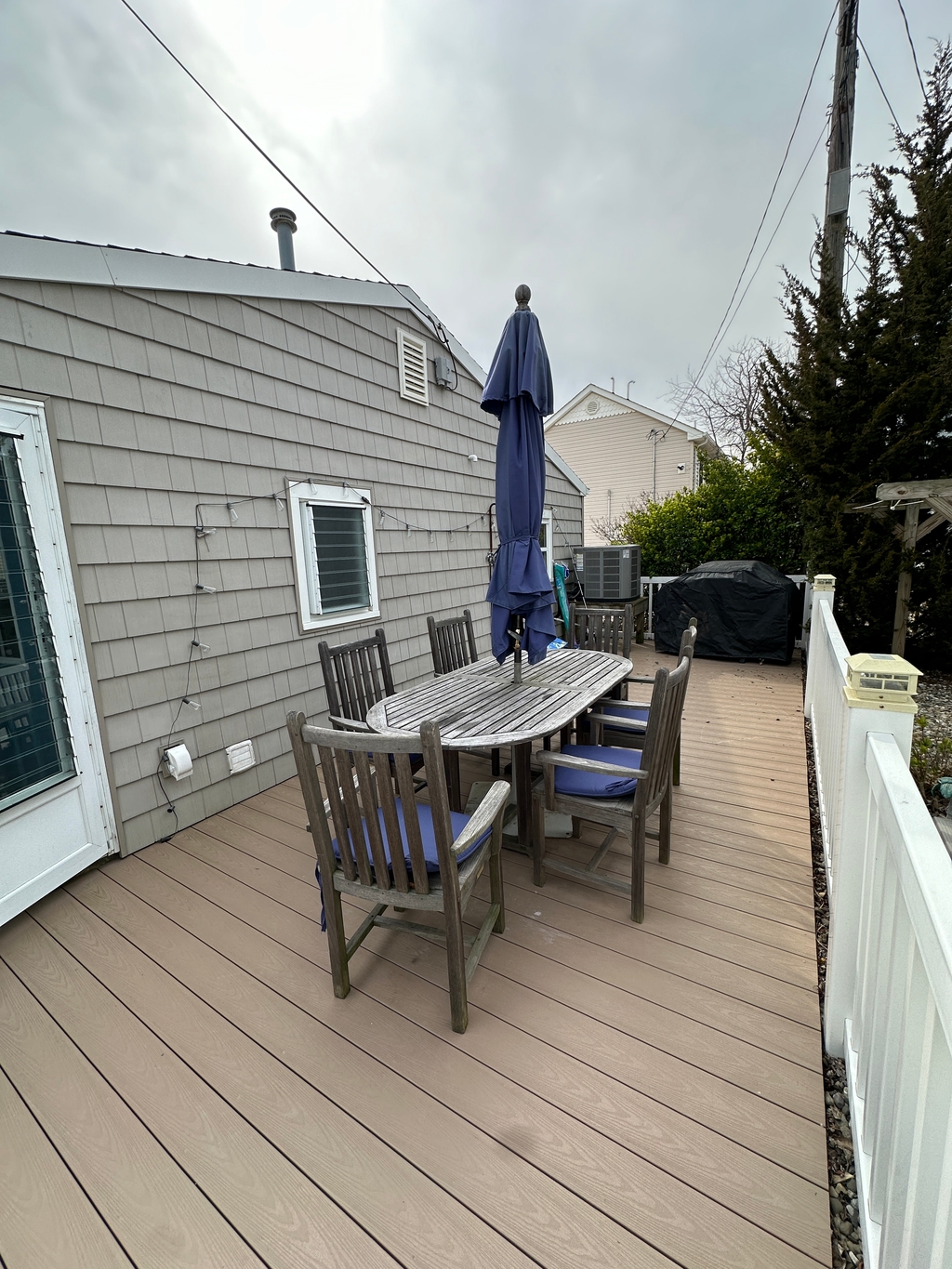 deck has a grill, table and chairs, umbrella, outdoor rinse station and games