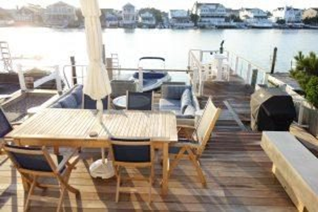 Multi-level waterfront decks include dining area, lower lounge area with fireplace table, pier with umbrella pub table and gangway gate, and floating dock for swimming, boating, and daydreaming. 